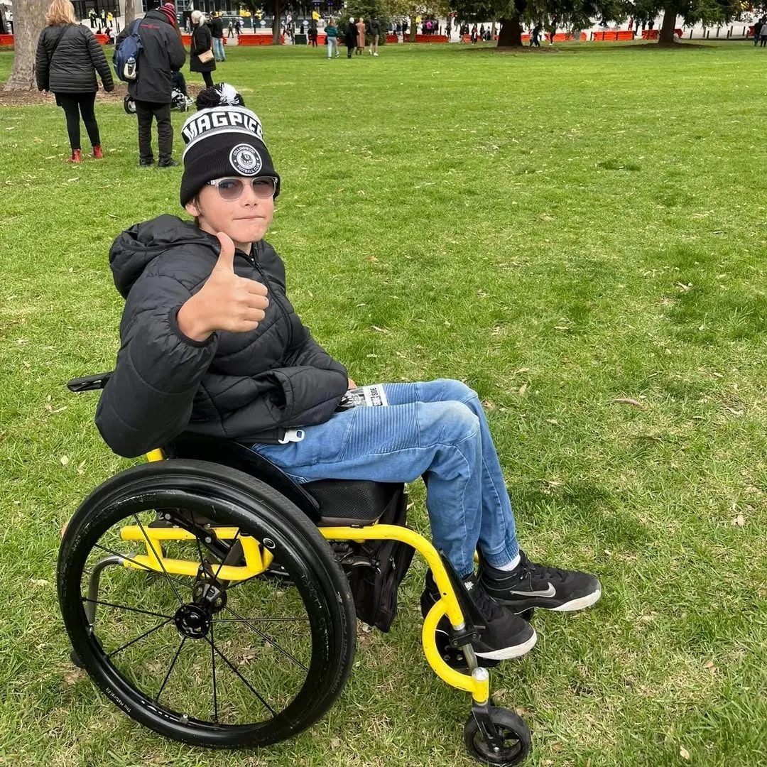 Participant in a wheelchair giving a thumbs up at the footy