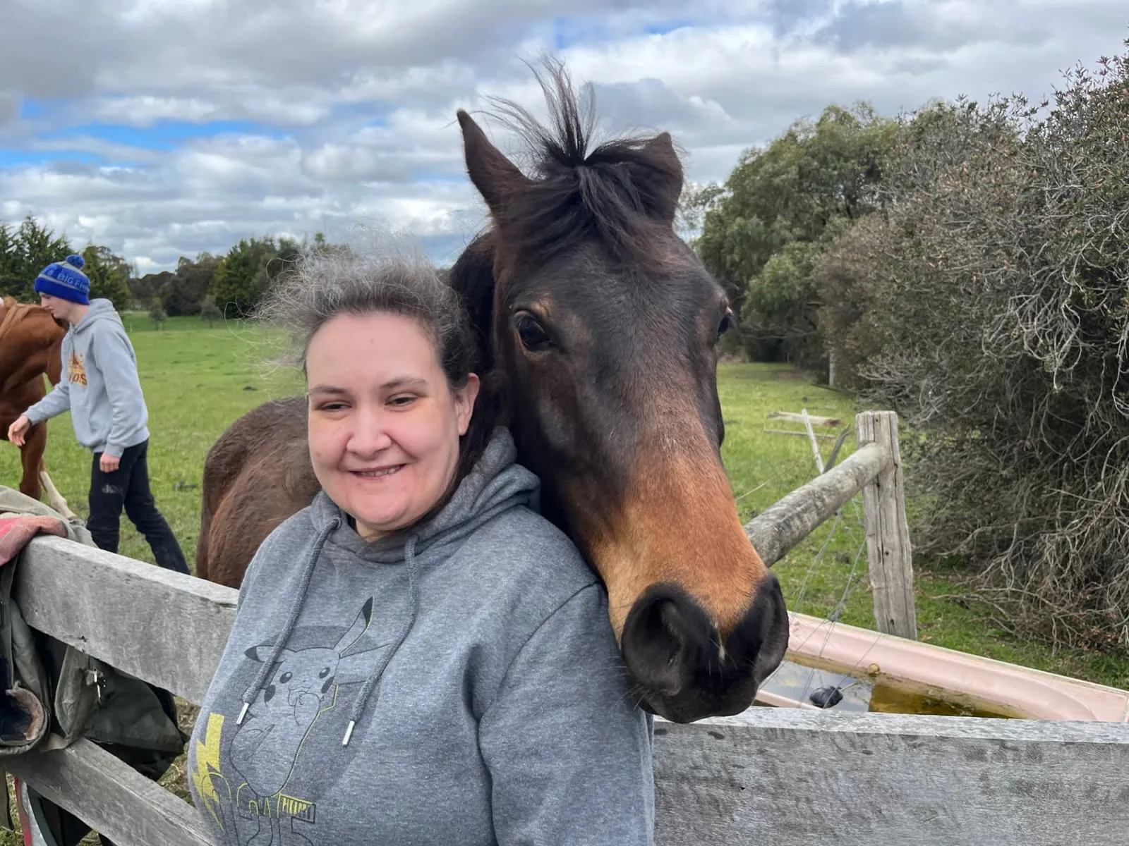 Participant smiling beside a horse at a farm